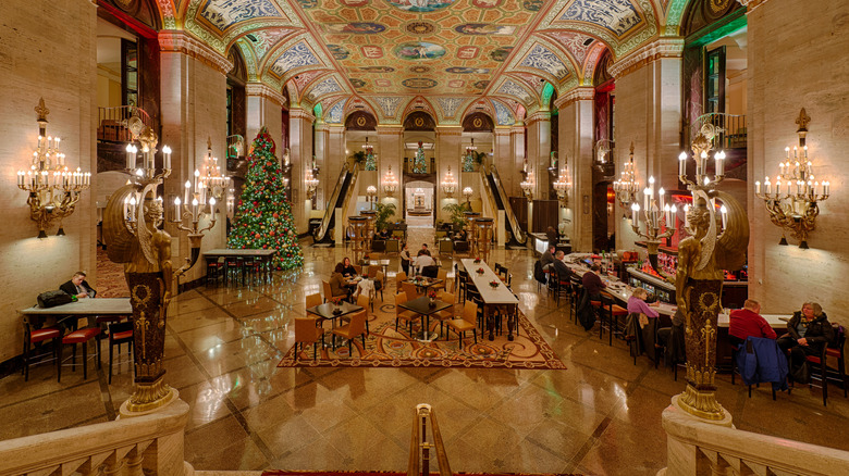the golden interior of a hotel lobby decorated with chairs, tables and a Christmas tree