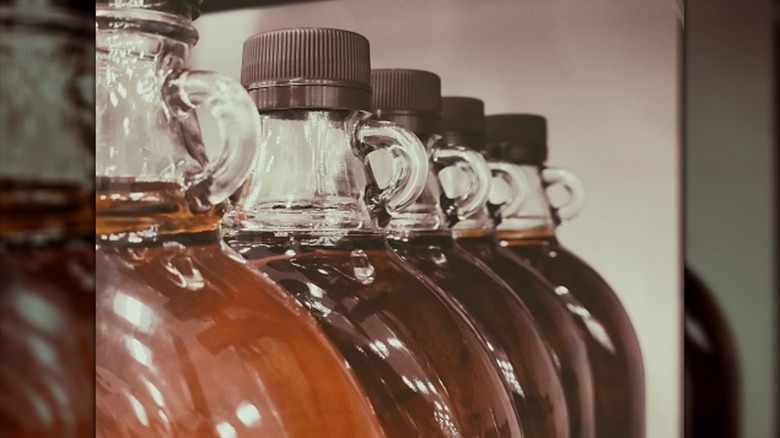 A photo of several maple syrup bottles in a row, focused on their round handles