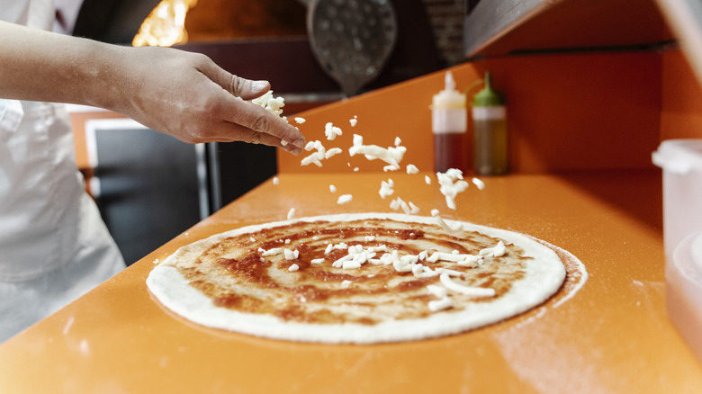 cheese going onto pizza