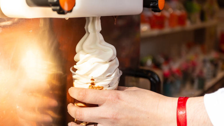 A person getting vanilla ice cream out of a machine