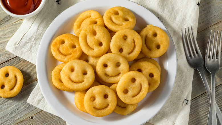 Smiley fries on plate with ketchup and forks