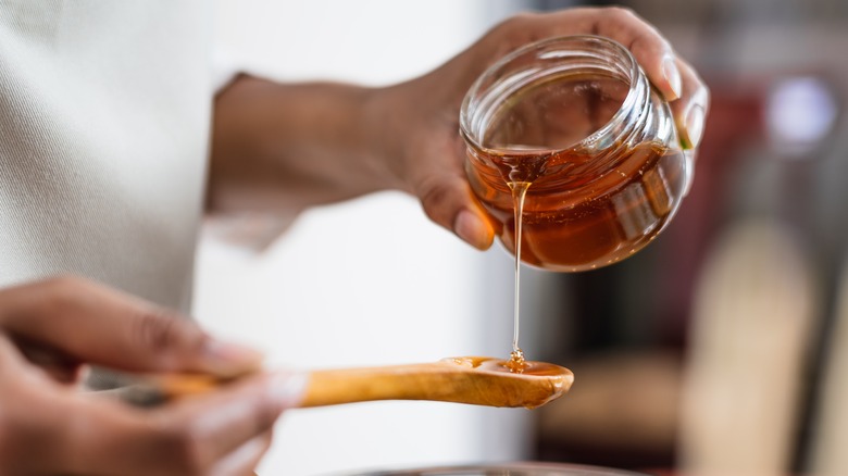 pouring jar of honey onto spoon