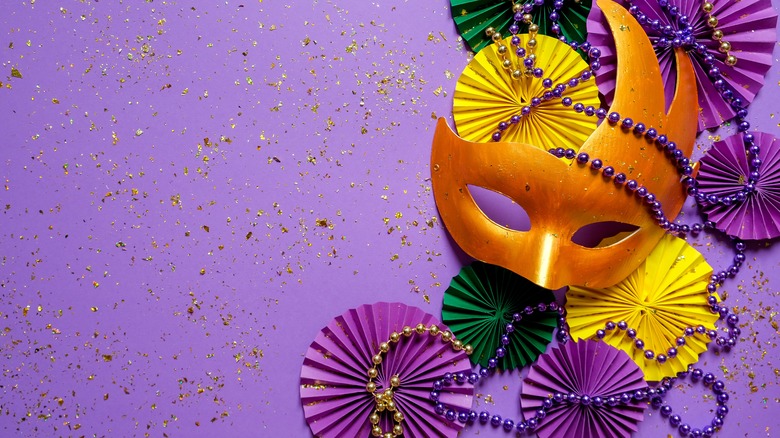 Mardi gras mask and beads on purple background