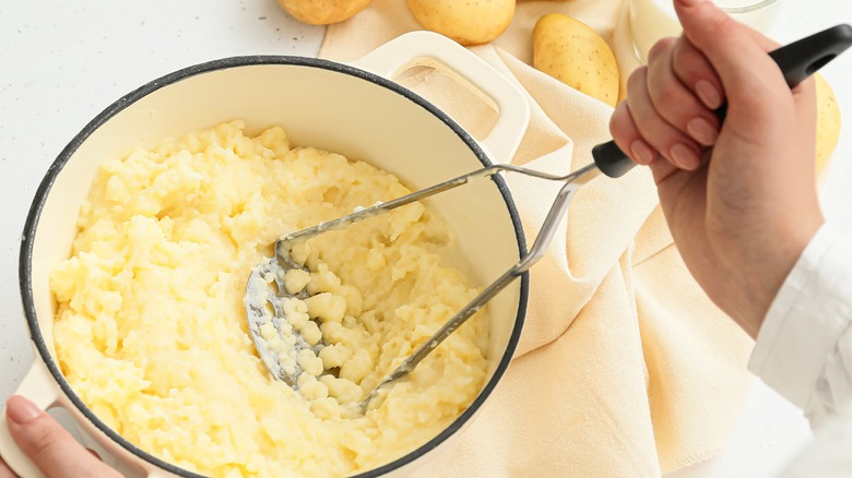 Close up of hand mashing potatoes