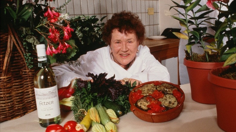 Julia Child smiles near food and wine