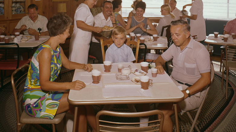 Vintage photo of two older people and a young boys sitting down for breakfast in a lodge