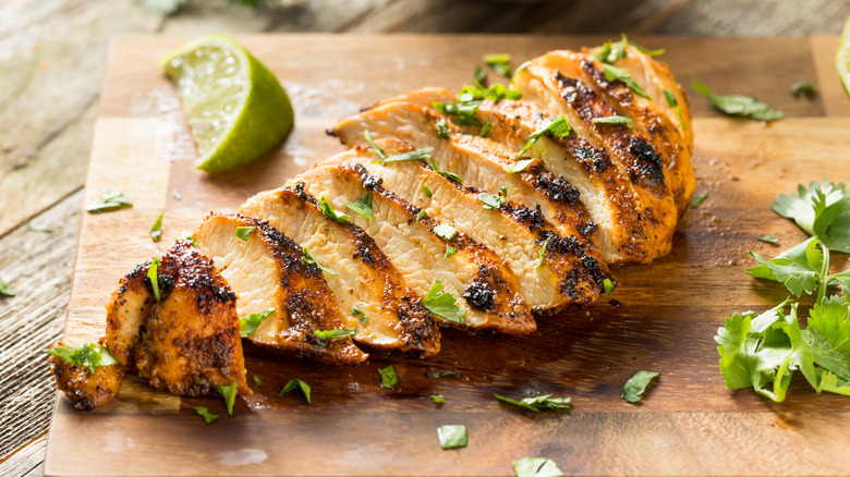 Sliced cooked chicken breast on a board