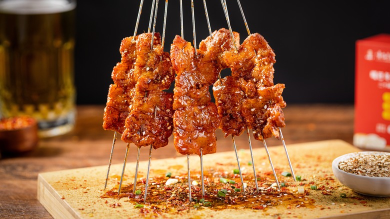 Skewers sticking out of a cutting board