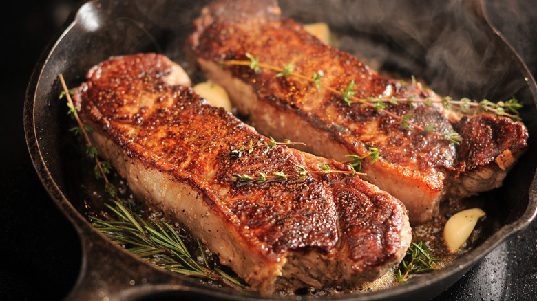 Two seared strip loins in a cast iron pan