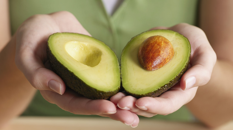 hands holding avocado halves