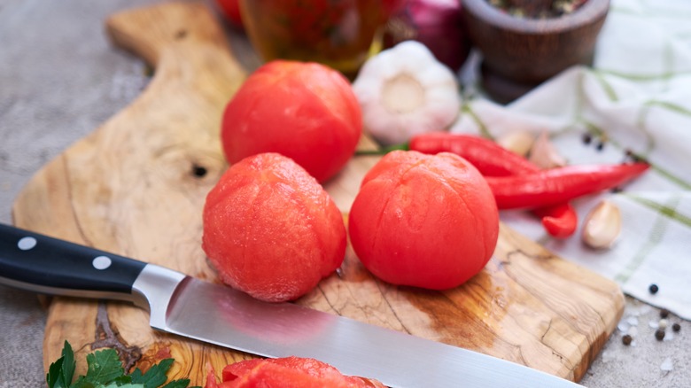 peeled tomatoes laying atop board