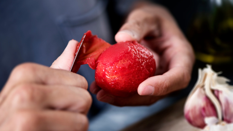 chef peeling tomato with knife