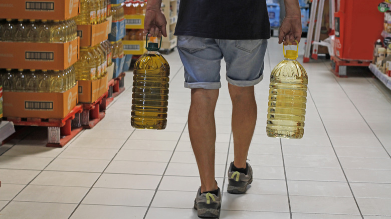 A man carrying bottles of oil at a supermarket.