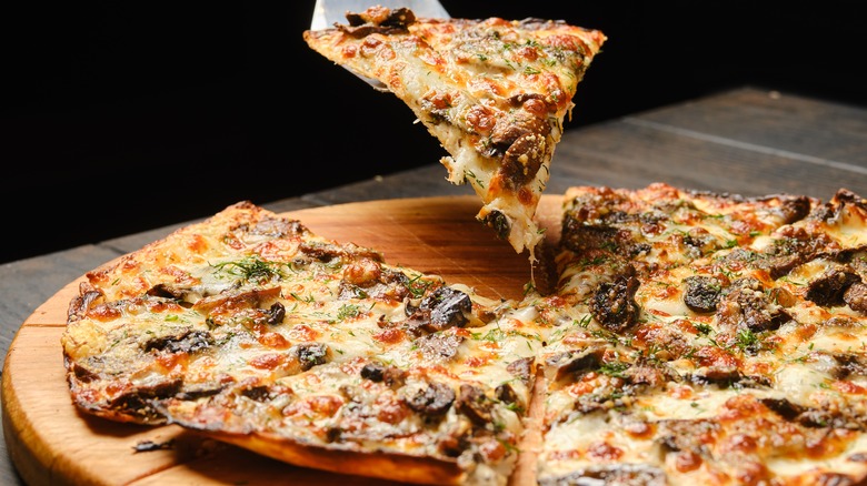 Lifted slice of pizza with vegetables and mushrooms