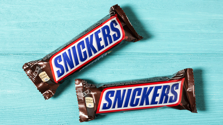 Two Snickers bars on a light blue background