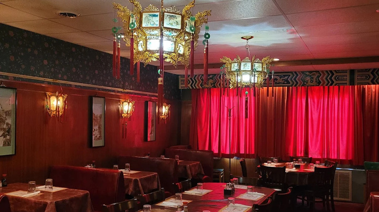Interior of the Cozy Inn restaurant, with orante light fixtures and red curtains