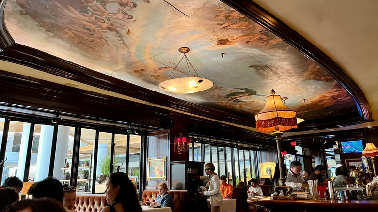 Interior of Old Ebbitt Grill restaurant, with polished wooden beams and a painted ceiling.