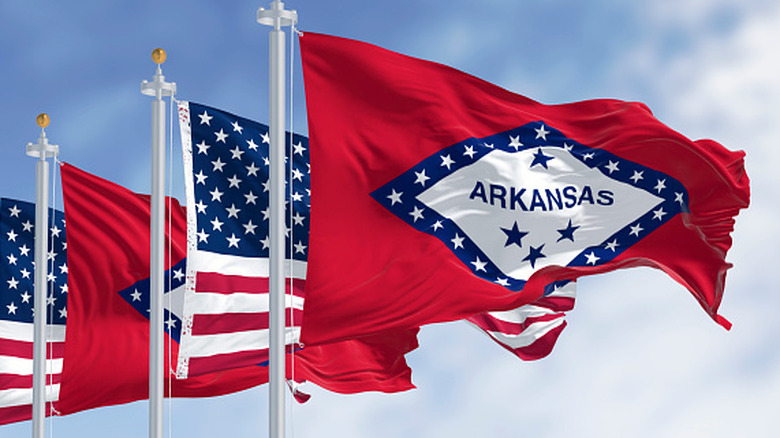 Arkansas flag blowing in the wind with American flag behind it