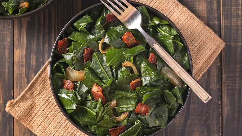 A bowl of cooked collard greens and bacon bits