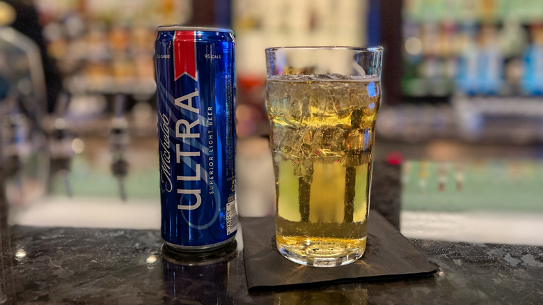 A can of Michelob Ultra Beer and a glass on a counter on a bar.
