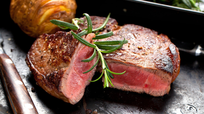 Sliced medium-rare steak with sprig of rosemary