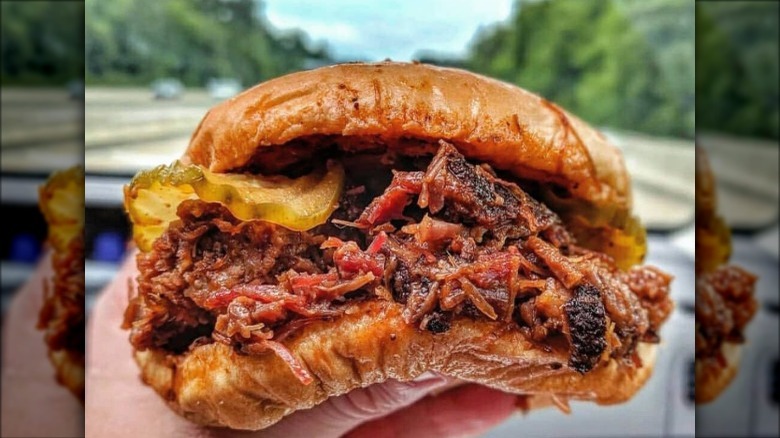 A person holding up a buccees brisket sandwich 