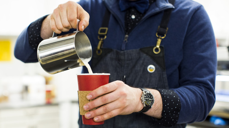 barista pouring milk into latte