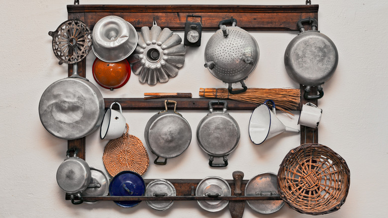 Vintage cookware and kitchen tools hanging off of a wooden wall rack