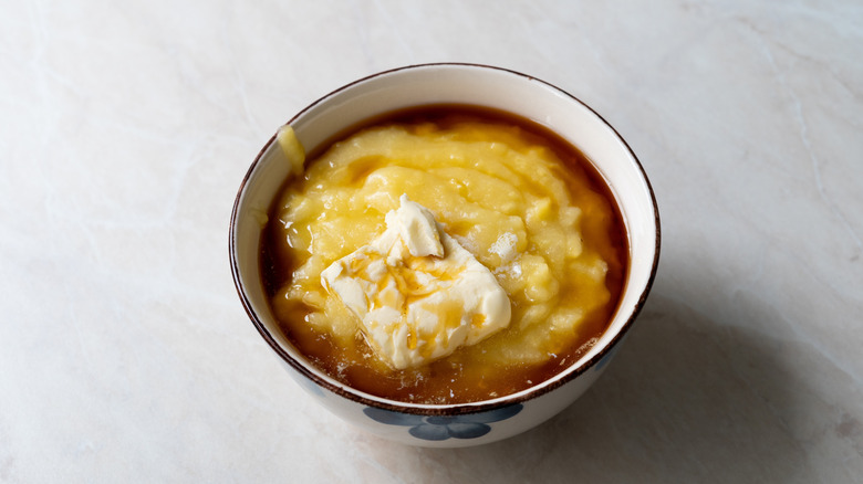 Bowl of cornmeal breakfast pudding topped with syrup