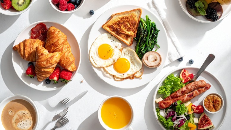 Table covered in breakfast dishes with various foods on them
