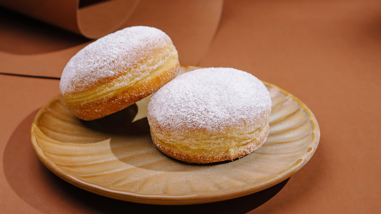 Donuts with powdered sugar on a brown plate