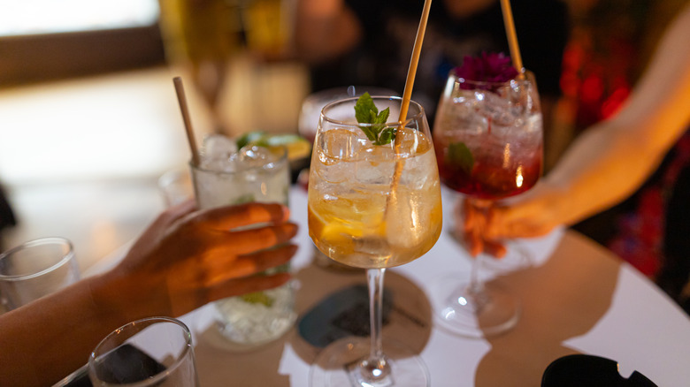 people clinking drinks together at dinner
