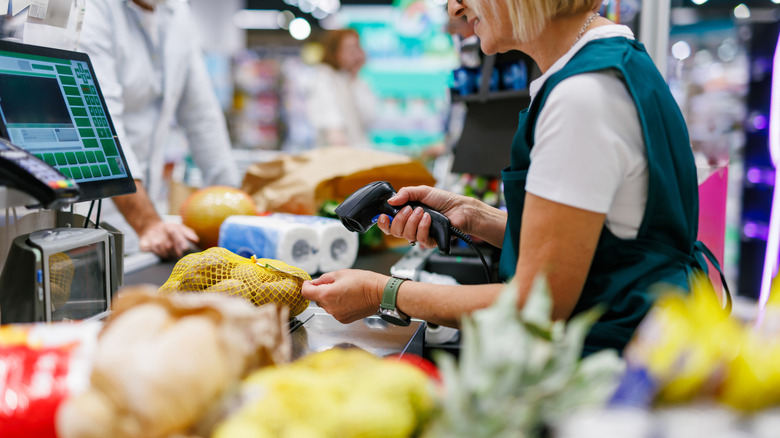 A female cashier scanning a sack of potatoes at a grocery store checkout line