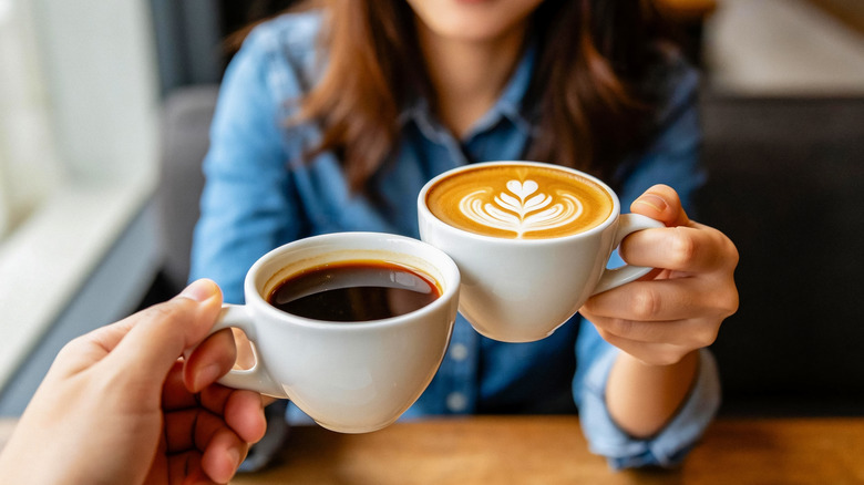 Close up of two people clinking espresso cups