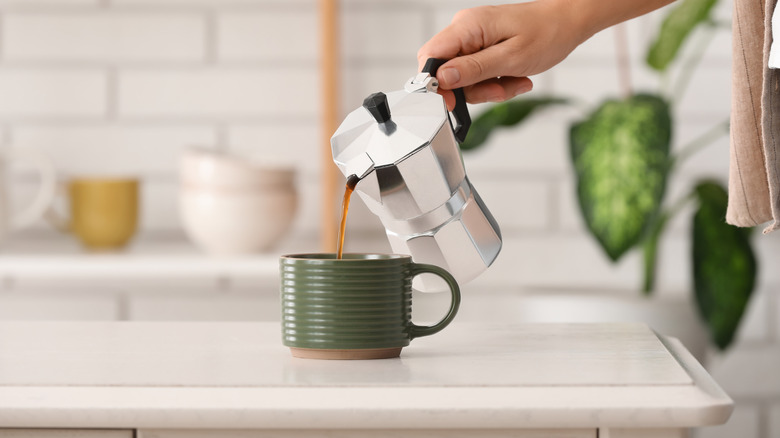 Person pouring espresso from a moka pot into a cup