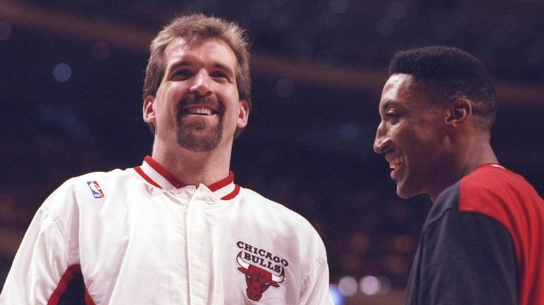 Bill Wennington in a Chicago Bulls jacket smiling and standing next to Scottie Pippen