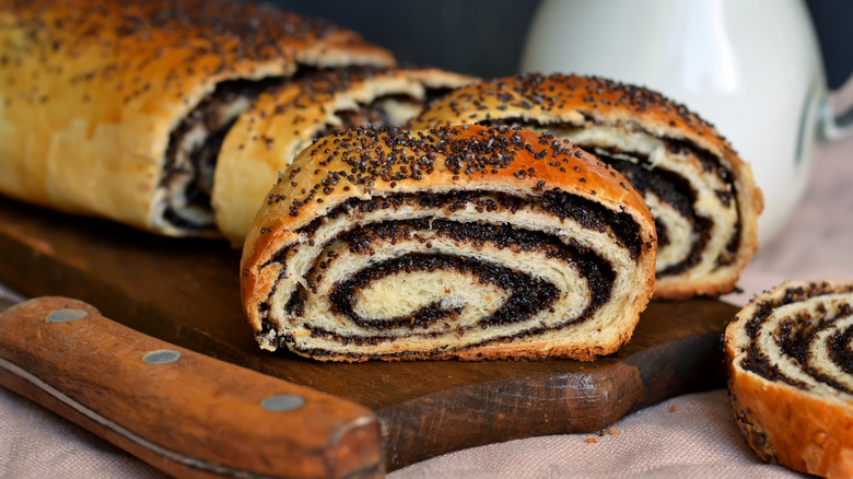 a sliced poppyseed and nut roll on a wooden board
