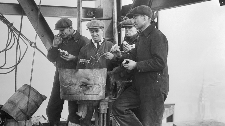 black and white photo of factory workers taking a break eating