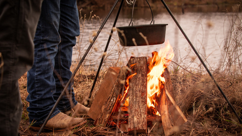 cowboys cooking food in a dutch oven
