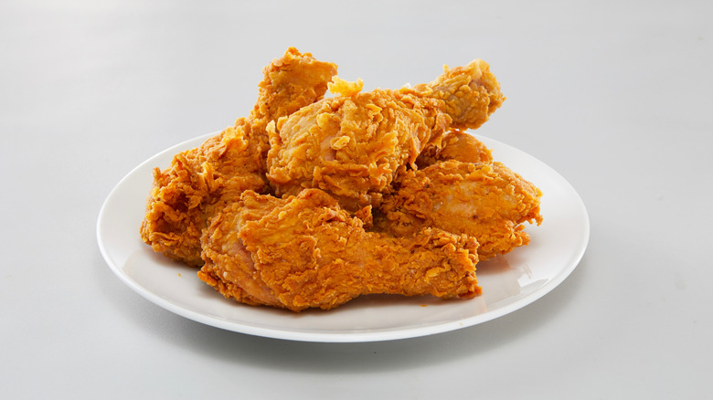 Pieces of fried chicken piled on a white plate.