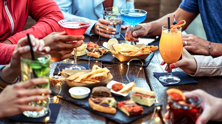 Group of friends enjoying appetizer drinking and eating in a bar