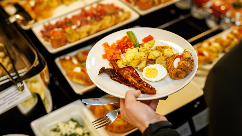 Guest picks up different food at the breakfast buffet
