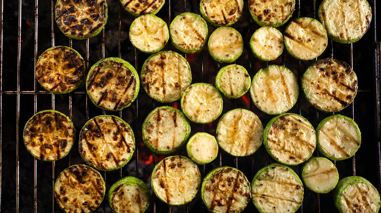 Round slices of zucchini cooking on a grill with grill marks seared on