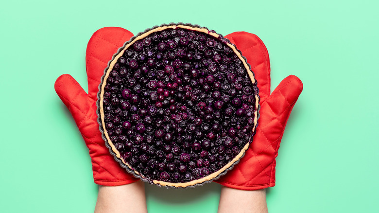 Blueberries pie with red oven mits