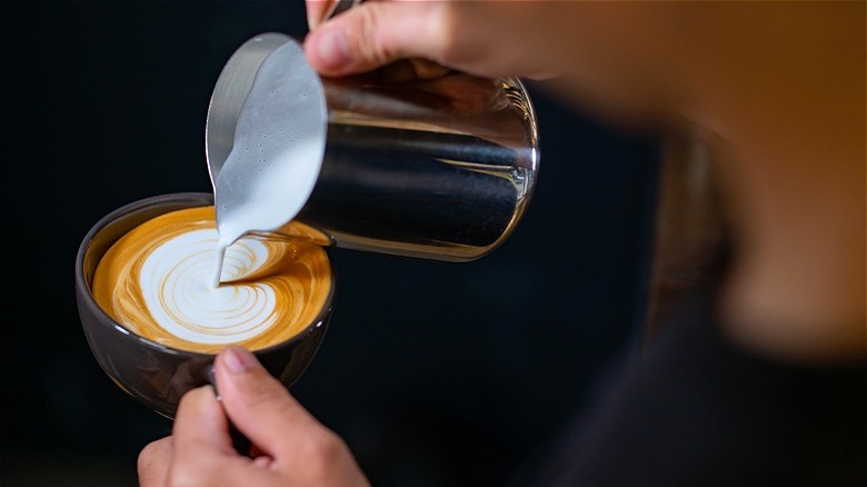 Hand pouring steamed milk