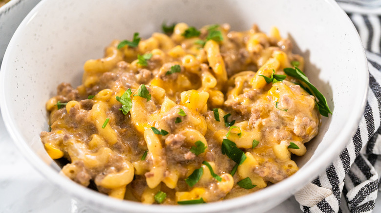 Homemade hamburger helper meal in a white bowl with a parsley garnish.