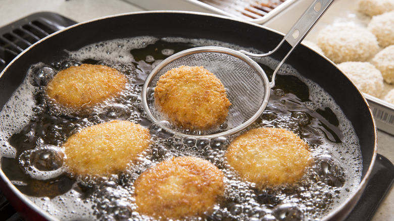 Slotted spoon holding frying croquette