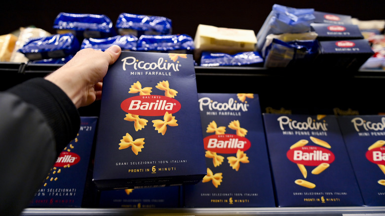 A person holding up a box of Barilla pasta in an Italian grocery store