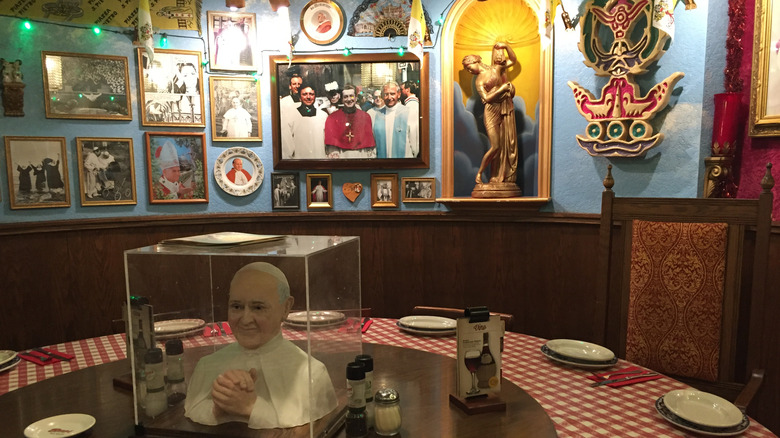 interior of a buca di beppo filled with tacky religious iconography, images of the pope