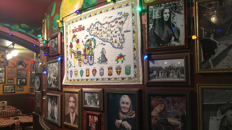 interior of buca di beppo featuring gallery wall of old photos and map of sicily